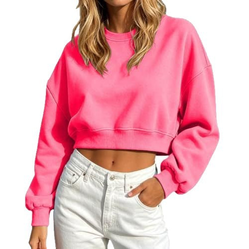 A woman wearing a bright pink cropped crewneck sweatshirt and white jeans, shown from the neck down against a plain white background.