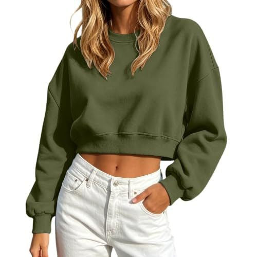 A woman wearing an olive green cropped crewneck sweatshirt and white jeans, shown from the neck down against a plain white background.