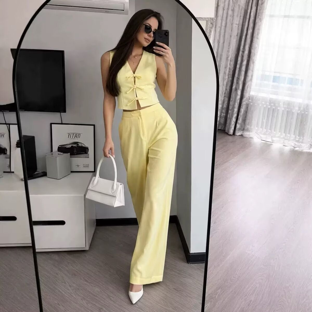 Yellow bow-tie vest and wide-leg trousers set - full outfit styled with handbag