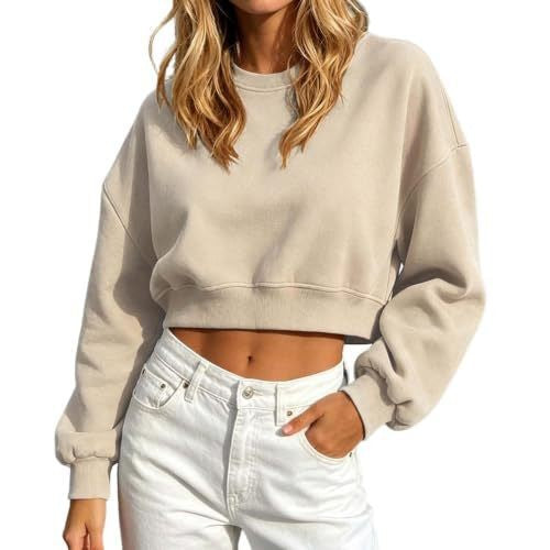 A woman wearing a light beige cropped crewneck sweatshirt and white jeans, shown from the neck down against a plain white background.